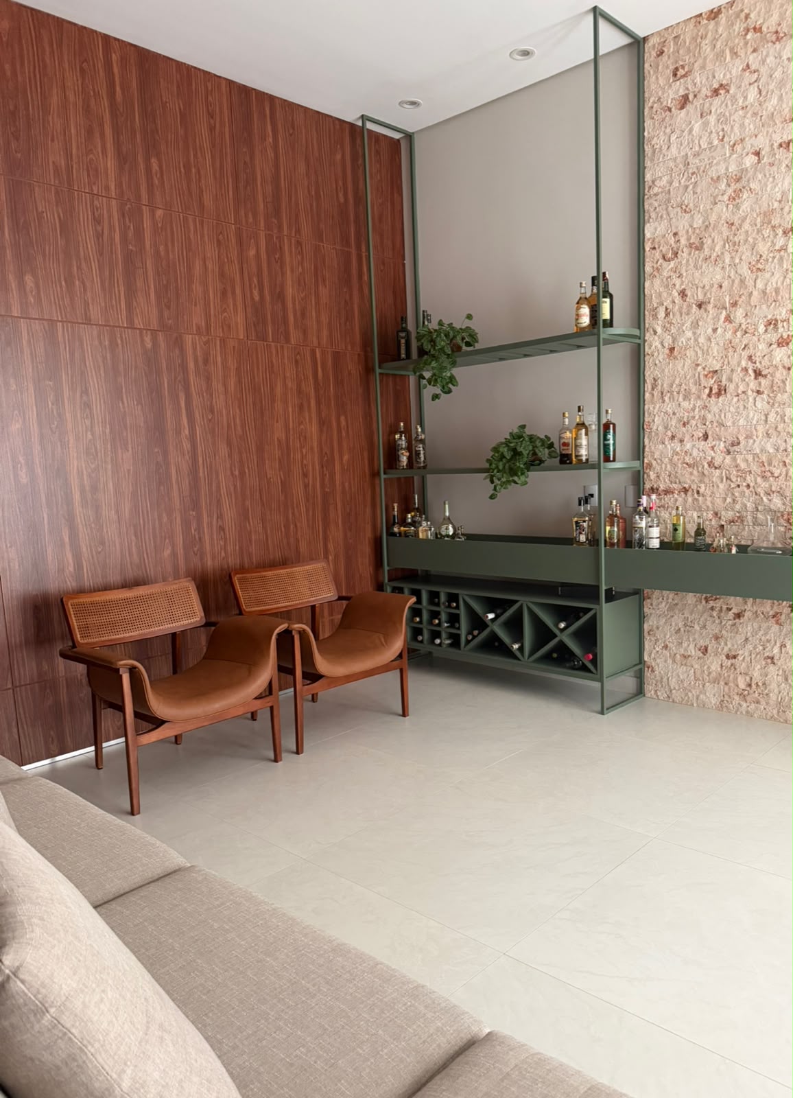 Sala de estar com bar, painel de madeira e parede de pedra
