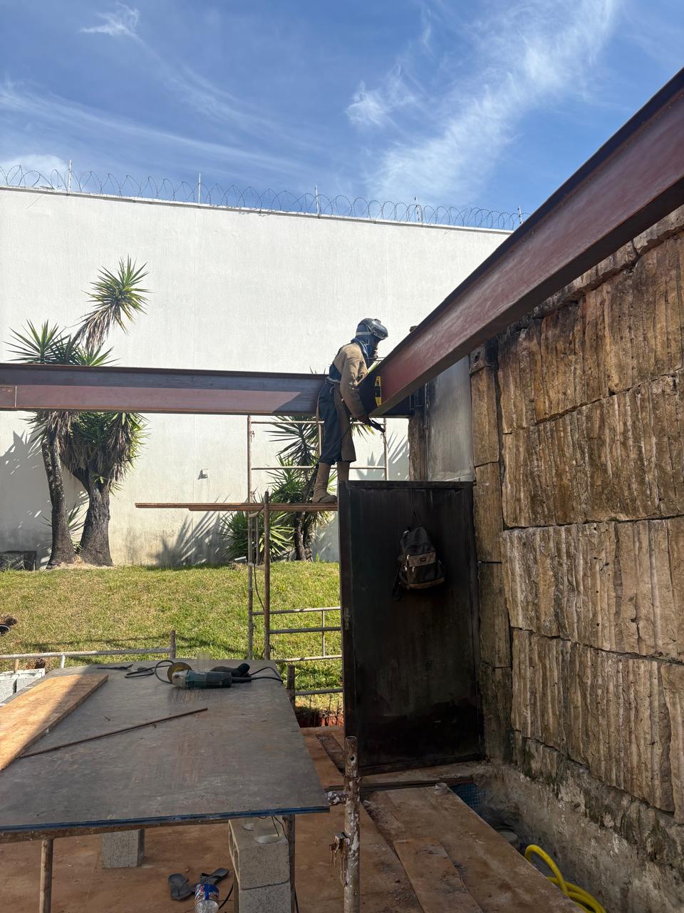 Soldador executando a ligação entre vigas sobre o andaime