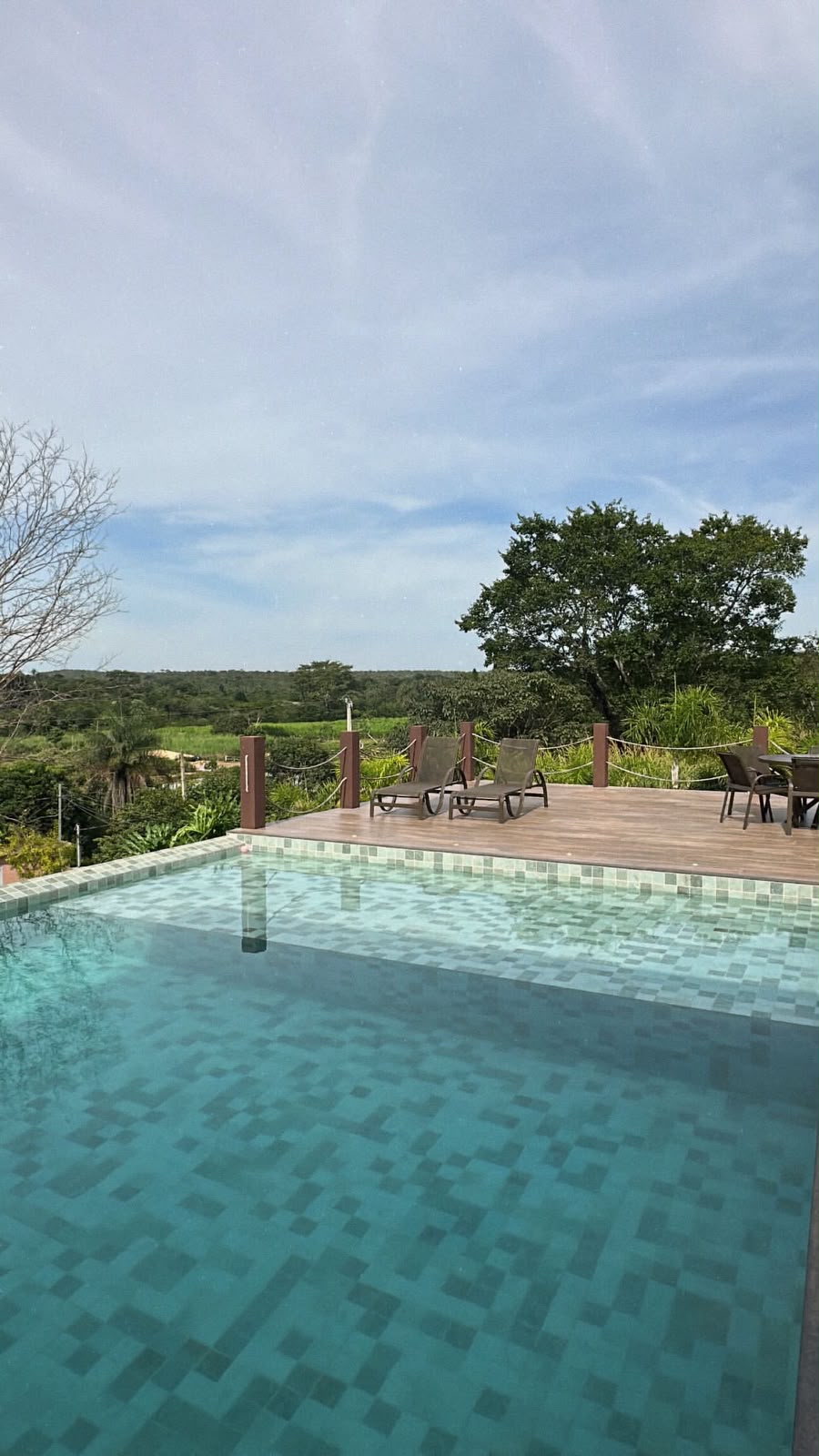 Piscina de borda infinita com deck de madeira e vista para o vale