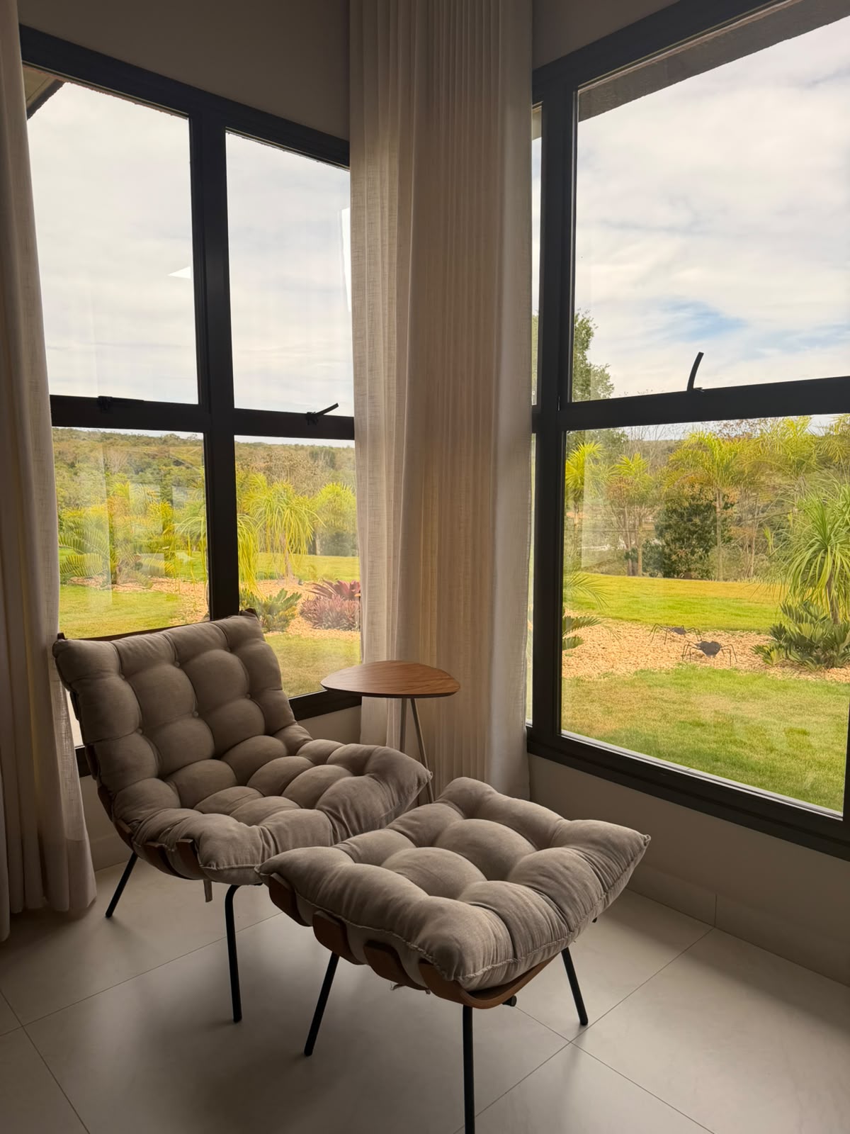 Poltrona junto à janela de canto, com vista para o jardim